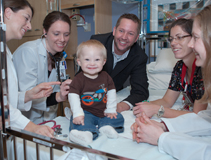 Family-centered rounds at American Family Children's Hospital. From left: pediatric hospitalist Michelle Kelly, MD; pediatric intern Leslie Riopel, MD; Ayden Hollman and his father Jake; an AFCH pediatric nurse; and senior pediatric resident Jennifer Hartwell, MD.